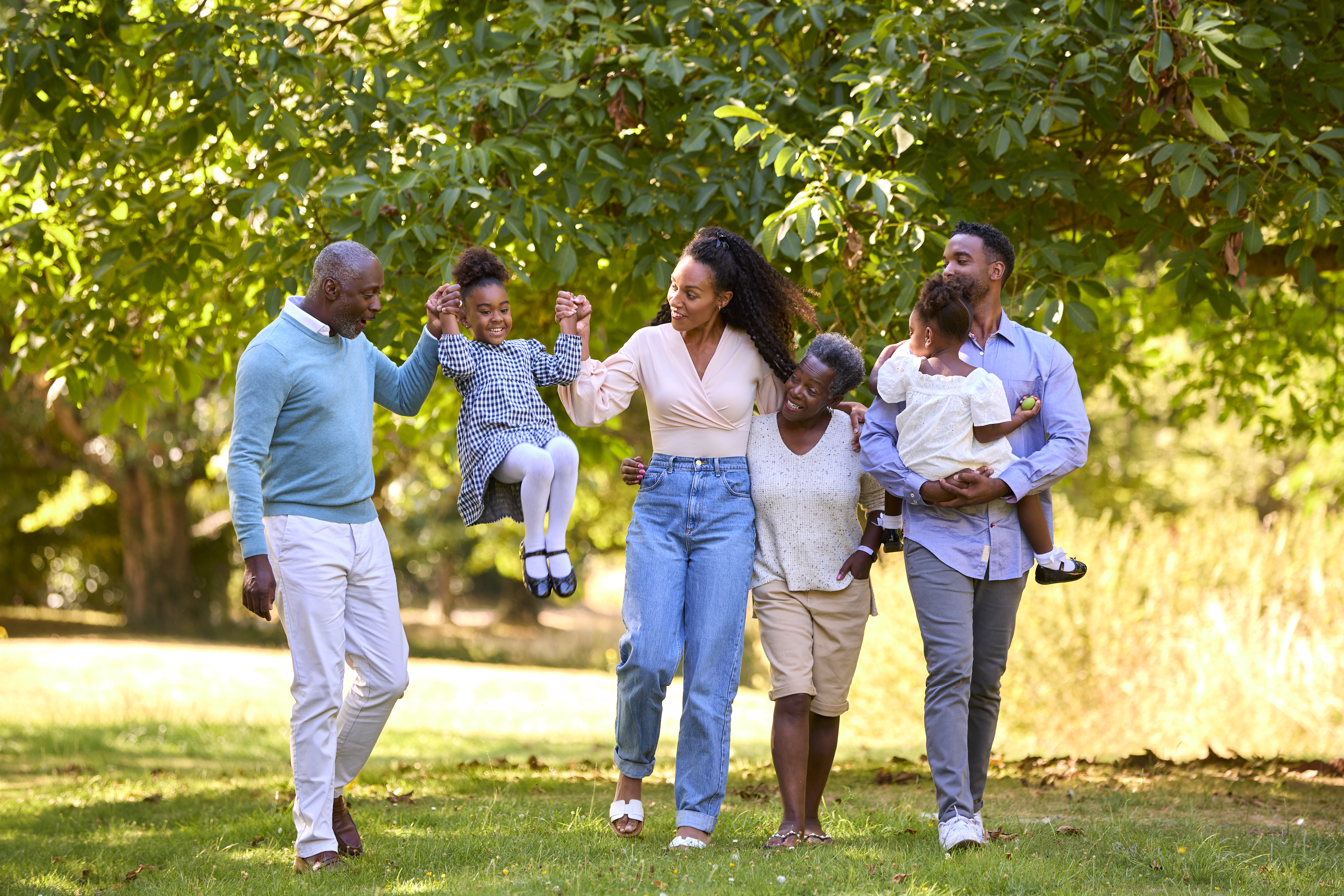 Multi-Generation Family Enjoying Walk In Countryside Together Swinging Granddaughter